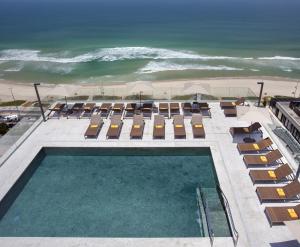 a swimming pool with lounge chairs and the ocean at Windsor Marapendi Hotel in Rio de Janeiro