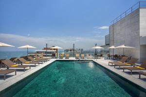 uma piscina com cadeiras e guarda-sóis num edifício em Windsor Marapendi Hotel no Rio de Janeiro
