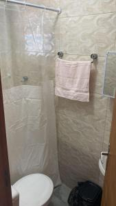 a bathroom with a shower with a toilet and a towel at Pousada Você No Guarujá in Guarujá +47 photos