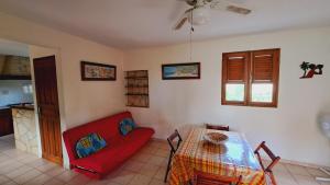 a living room with a red couch and a table at Le Pavillon des Alizés in Gourbeyre