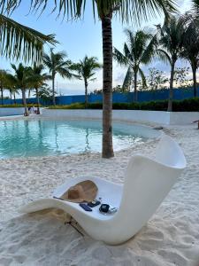 a beach chair on the sand next to a swimming pool at Sam's Chic Space - An Aesthetic Getaway in Angeles