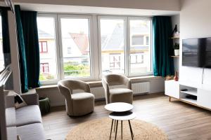 a living room with two chairs and a tv at 2-slaapkamer app. Middelkerke in Middelkerke