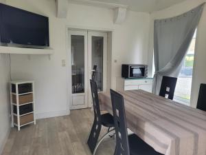 a dining room with a table with chairs and a television at Gîte à Romagné in Romagné