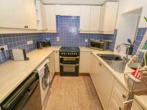 eine Küche mit weißen Schränken und einem schwarzen Herd mit Backofen in der Unterkunft Detached cottage near to Abersoch in Abersoch + 2 Fotos