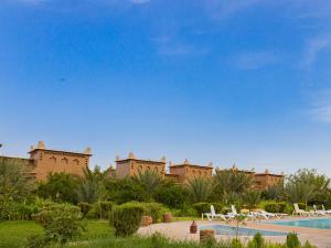 a resort with a swimming pool in front of a building at Maison D'h&ocirc;te Amridil in Skoura