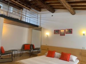 a bedroom with a bed with orange pillows and chairs at B&B La Casa Di Tufo in Orvieto