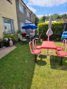 eine Gruppe Stühle, ein Tisch und ein Sonnenschirm in der Unterkunft Cuisinease in Ollerton