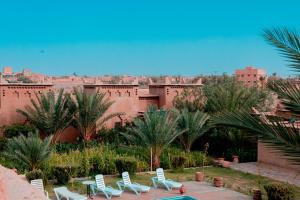 a group of chairs and palm trees in front of a building at Maison D'h&ocirc;te Amridil in Skoura