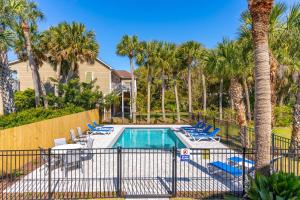 una piscina con sedie a sdraio e palme di Down River a Edisto Island