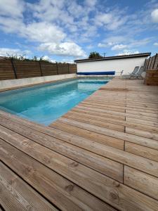 a swimming pool with a wooden deck at Cerisier in Étusson