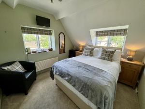 una camera con un letto e una sedia e due finestre di Guiting Guest House a Guiting Power