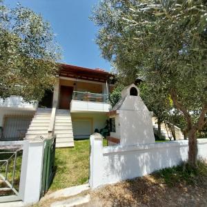 a house with a white fence and a tree at Olive Tree Villa in Nikiti