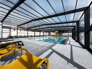 a swimming pool with a glass ceiling and yellow chairs at Camping La Chênaie in Les Mathes