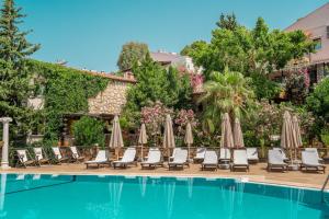a group of chairs and umbrellas next to a swimming pool at True Blue Boutique Hotel Kalkan in Kalkan
