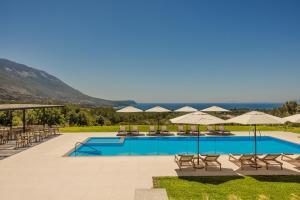 卡拉瓦杜斯罗迪一室公寓的一个带桌椅和遮阳伞的游泳池