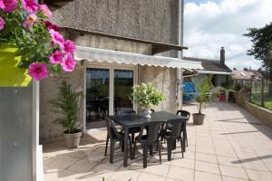 a black table and chairs on a patio with flowers at Comme chez soi en Champagne in Fromentières