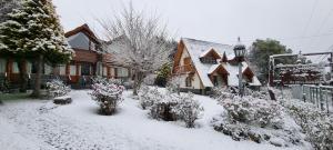 a yard covered in snow with flowers in front of a house at De las Rosas Bariloche in San Carlos de Bariloche
