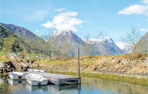 three boats docked at a dock on a river with mountains at Stunning Home In Fjærland in Fjarland