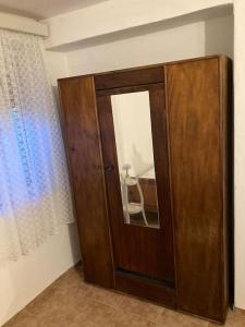 a wooden cabinet in a room with a mirror at Vila Klara room - garden view in Olib