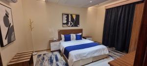 a bedroom with a bed with blue pillows and a window at سجى الهدوء للشقق المخدومة in Abha +17 photos