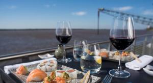 a table with two glasses of wine and sushi at Alojate en METRA Puerto Norte, luminoso estudio con pileta, gym y balcon in Rosario