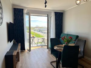 Una sala de estar con mesa y sillas y un balcón. en Apartament Happy, en Busko-Zdrój