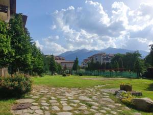 a grassy field with buildings and mountains in the background at IG Apartments Royal Towers 426 in Bansko