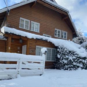 a wooden house with a white fence in the snow at Pajaro Azul in San Carlos de Bariloche
