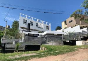 a white building with a fence in front of it at Sierra Alta Carlos Paz in Villa Carlos Paz