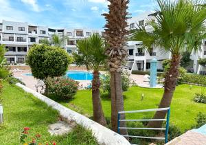 a resort with palm trees and a swimming pool at Appartement Familial - CaboNegro in Cabo Negro