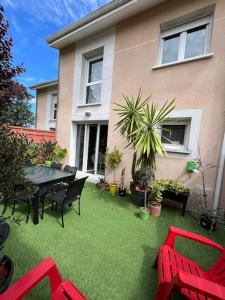 a patio with a table and chairs and a house at Jolie maison paisible in Gujan-Mestras