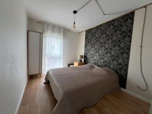 a bedroom with a bed and a black and white wall at Jolie maison paisible in Gujan-Mestras