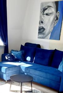 a blue couch in a living room with a picture of a woman at Gold Apartament in Wałbrzych