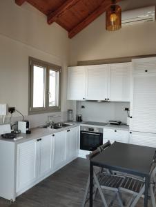 a kitchen with white cabinets and a table and a window at Costa Meganisi in Meganisi