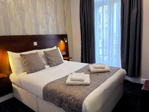 a hotel room with a bed with two towels on it at Lidos Hotel in London