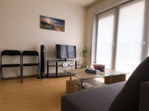 a living room with a couch and a tv at Cozy studio with pool close to the sea in Ostend