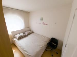 a small bedroom with a bed and a chair at Cozy studio with pool close to the sea in Ostend
