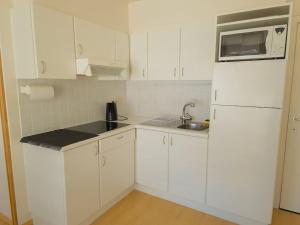 a white kitchen with a sink and a refrigerator at Cozy studio with pool close to the sea in Ostend