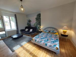 a bedroom with a bed and a chair and a couch at Gîte de la Vallée du Don in Guéméné-Penfao