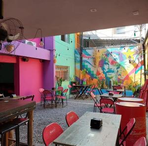 a room with tables and chairs and a colorful wall at Ramon Hostel Bar in Recife