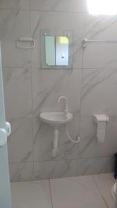 a white bathroom with a sink and a mirror at Jangaloa in Jijoca de Jericoacoara