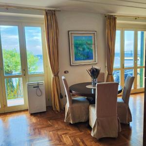 una sala da pranzo con tavolo, sedie e finestre di Scarlet Flower - Lago Maggiore a Meina