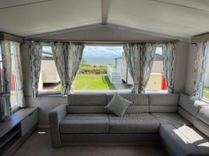 Una sala de estar con un sofá y una ventana grande. en Robinson retreats beautiful caravan with sea views pet friendly, en Mainsriddle