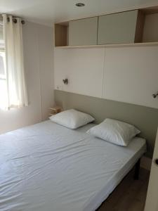 a bed with two pillows on it in a room at CAMPING RÊVE DES ILES in Argelès-sur-Mer +72 photos