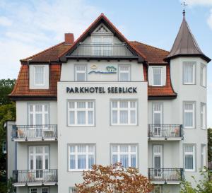 un gran edificio blanco con una señal para parkorth Seelket en Parkhotel Seeblick en Warnemünde