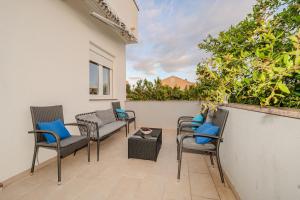 eine Terrasse mit Stühlen und einem Tisch an der Wand in der Unterkunft Apartmani DALI in Novalja