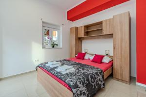 Schlafzimmer mit einem großen Bett mit roter und schwarzer Bettwäsche in der Unterkunft Apartmani DALI in Novalja