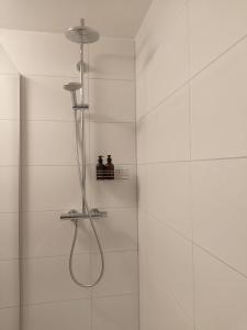 eine Dusche in einem weiß gefliesten Bad in der Unterkunft Ferienwohnung mit Balkon I Bergblick I Parkplatz Apartment ONE in Bad Hindelang