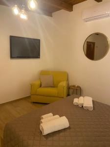 a living room with a yellow couch and towels on a bed at Brezza marina in Taranto