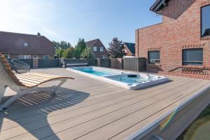 a deck with a bench and a swimming pool at Luxus 5 Sterne Ferienhaus Arngast in Norden